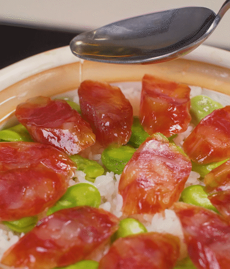 大米出現(xiàn)小孔時開蓋放香腸，往鍋邊淋入少許油，再燜煮8~10分鐘左右。