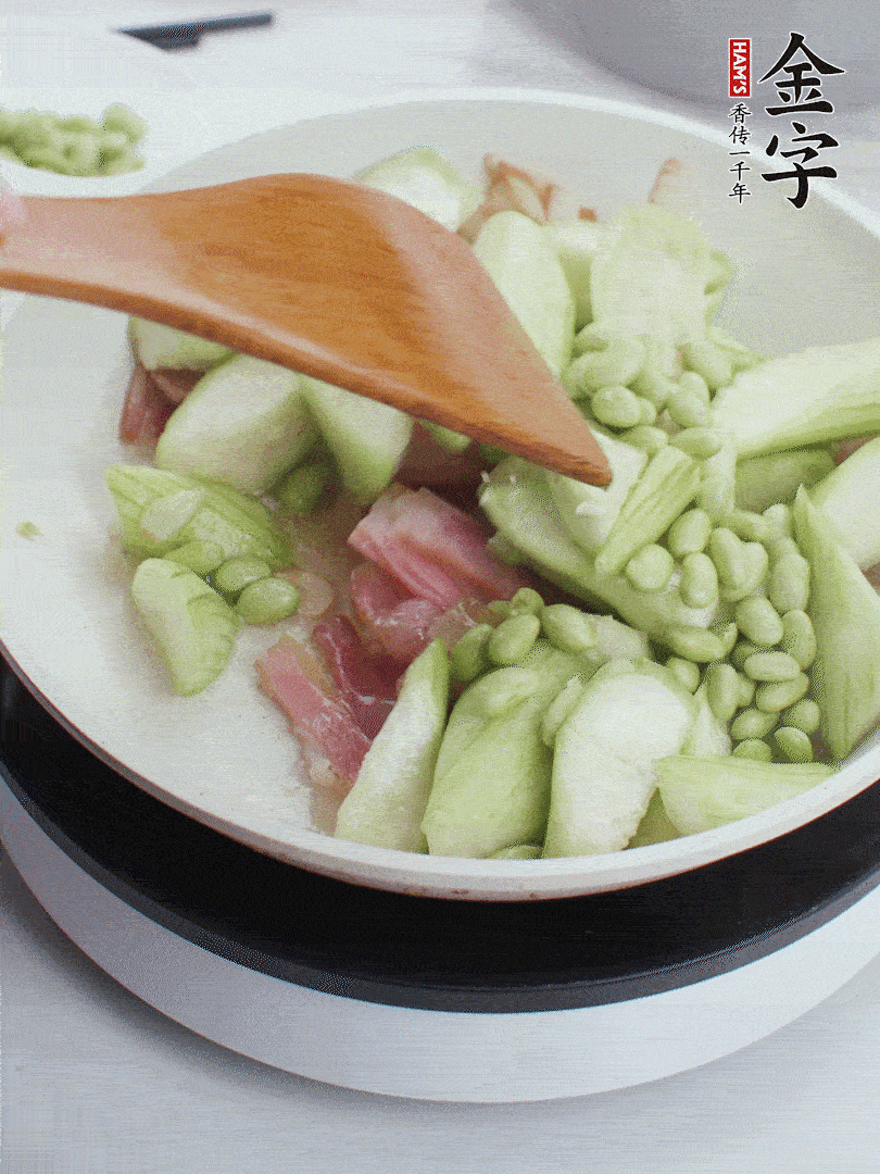 依次下絲瓜、青豆翻炒，炒至絲瓜打蔫縮小。
