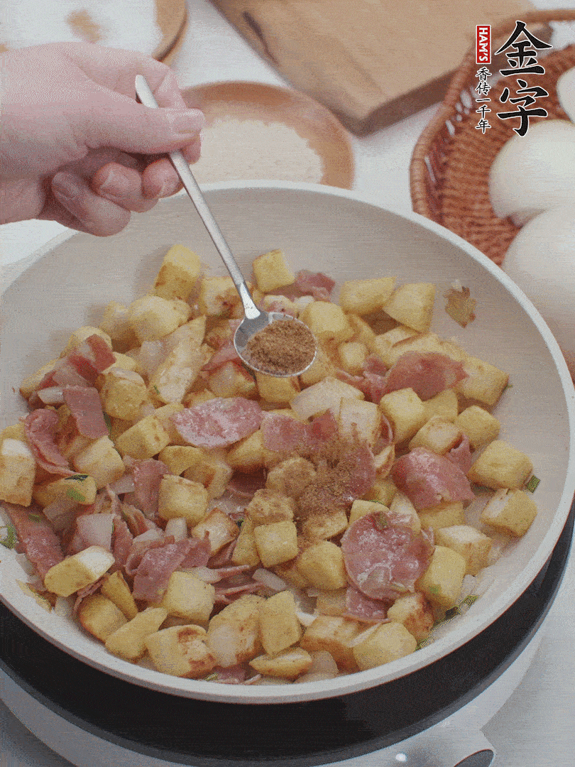 起鍋少油，煸香洋蔥丁、蔥白，加入金字培根火腿翻炒幾下，再加入饅頭丁、1小勺孜然粉、少許鹽翻炒均勻并鋪平。